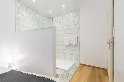 a bathroom with white tile walls and a shower at Florella Marceau Apartment in Cannes