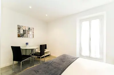 a bedroom with a bed and a table and chairs at Florella Achard Apartment in Cannes