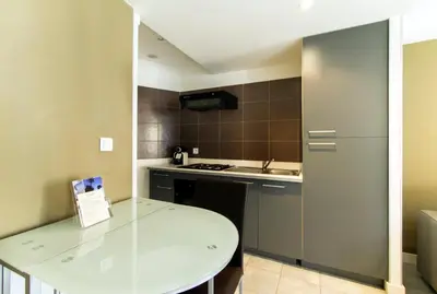a small kitchen with a white table and a refrigerator at Florella Achard Apartment in Cannes