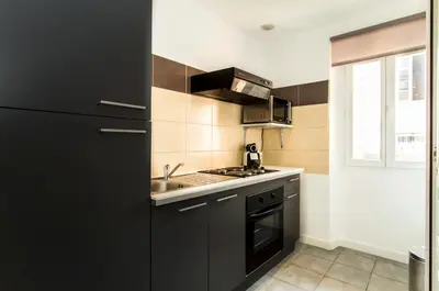 a kitchen with black cabinets and a sink at Florella Achard Apartment in Cannes