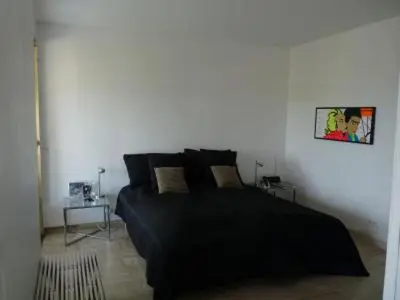 a bedroom with a large black bed and a table at Two Bed apartment in a gated residence with gardens in Cannes with sea views 865 in Cannes