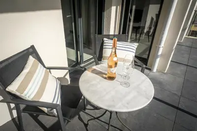 a bottle of wine sitting on a table with two chairs at Modern 1-Bed Apt near Croisette Palais - 1903 in Cannes