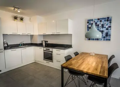 a kitchen with white cabinets and a wooden table at Modern 1-Bed Apt near Croisette Palais - 1903 in Cannes