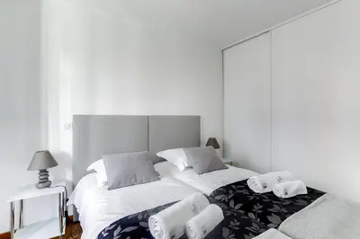 a white bedroom with two beds and a lamp at IMMOGROOM - 8 min from the Palais - AC - Quai St Pierre in Cannes