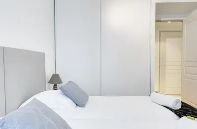 a white bedroom with a bed and a mirror at IMMOGROOM - 8 min from the Palais - AC - Quai St Pierre in Cannes