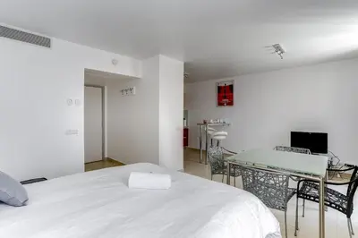 a white bedroom with a bed and a table at IMMOGROOM - 8 min from the Palais - AC - Quai St Pierre in Cannes
