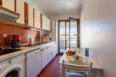 a kitchen with white cabinets and a table with a plate of food at Residence Gray d'Albion 2P BLA584 in Cannes