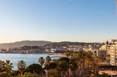 a city with palm trees and a body of water at Rabelais in Cannes