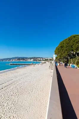 a sandy beach with a pier in the background at Rabelais in Cannes