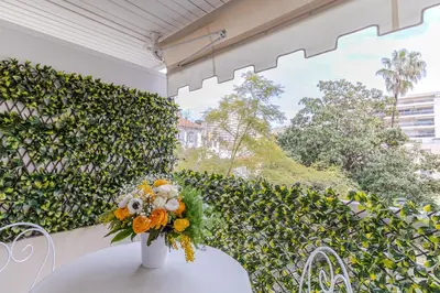 a vase of flowers sitting on a table in front of a hedge at Appartement CANNES IMPERIAL Pointe Croisette in Cannes