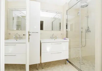 a white bathroom with two sinks and a shower at Appartement CANNES IMPERIAL Pointe Croisette in Cannes