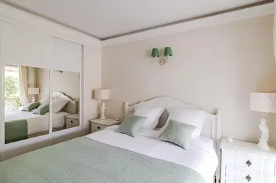 a white bedroom with a bed and a mirror at Appartement CANNES IMPERIAL Pointe Croisette in Cannes