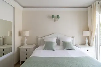 a white bedroom with a bed with two pillows at Appartement CANNES IMPERIAL Pointe Croisette in Cannes