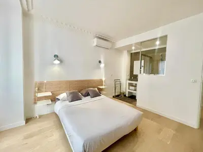 a bedroom with a white bed and a mirror at Pasteur by Welcome to Cannes in Cannes