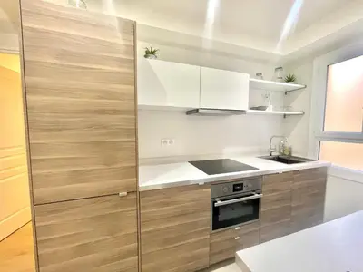 a kitchen with white and wooden cabinets and a sink at Pasteur by Welcome to Cannes in Cannes