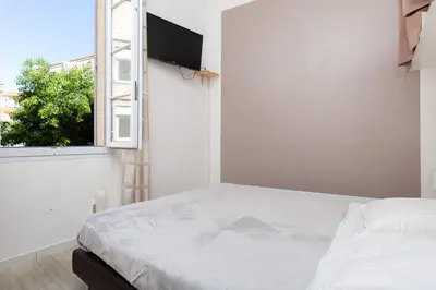 a white bedroom with a bed and a window at Forville in Cannes