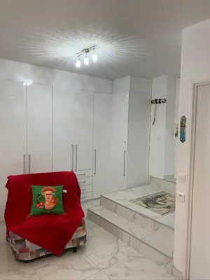 a white room with a red pillow on a chair at Cannes Apartment close to Congress Palace, Croisette, Beaches in Cannes