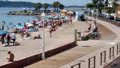 a group of people on a beach with umbrellas at Cannes - Beachfront with private garden - Palm Beach Croisette in Cannes