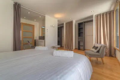 a bedroom with a large white bed and a chair at IMMOGROOM - Beautiful duplex - Sea view - Quiet - AC - Wifi - Garage in Cannes