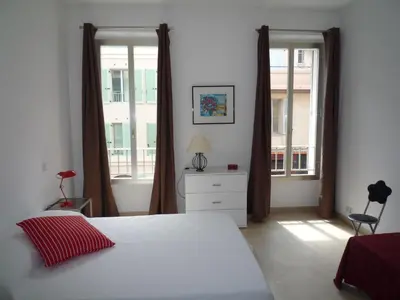 a bedroom with a bed and two large windows at Alouette in Cannes