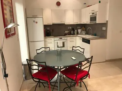 a kitchen with a table and chairs and a kitchen with white cabinets at Alouette in Cannes