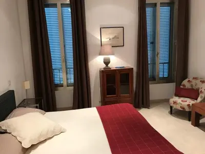 a bedroom with a bed and a chair and windows at Alouette in Cannes