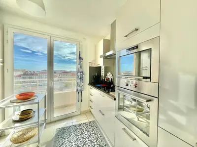 a kitchen with white cabinets and a large window at Bristol by Welcome to Cannes in Cannes