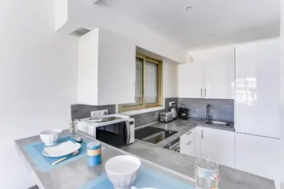 a kitchen with white cabinets and a counter top at IMMOGROOM - Renovated apartment - Terrace - AC - Wifi in Cannes