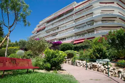 a red park bench in front of a building at Fully equipped appartment 105 m2 clear view on the sea and californie hills in Cannes