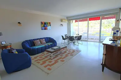 a living room with a blue couch and a table at Fully equipped appartment 105 m2 clear view on the sea and californie hills in Cannes