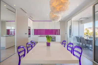 a dining room with a large white table and purple chairs at Cannes Vieux Port in Cannes