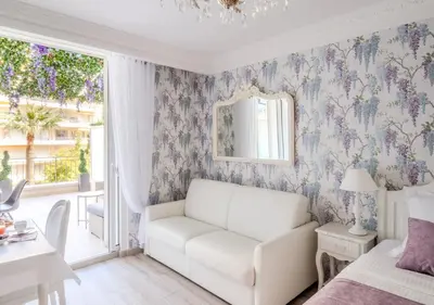 a living room with a white couch and floral wallpaper at Cannes Imperial Croisette Palais Miramar in Cannes