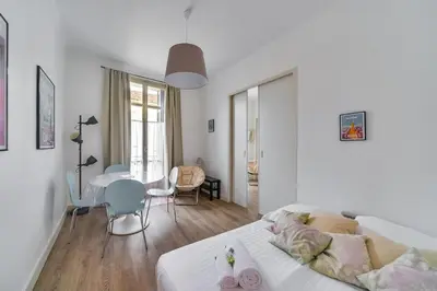 a white bedroom with a bed and a table and chairs at IMMOGROOM- Close to the Palais des festivals- Wifi in Cannes