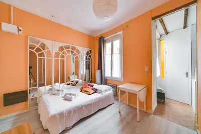 a bedroom with orange walls and a bed and a table at IMMOGROOM- Close to the Palais des festivals- Wifi in Cannes