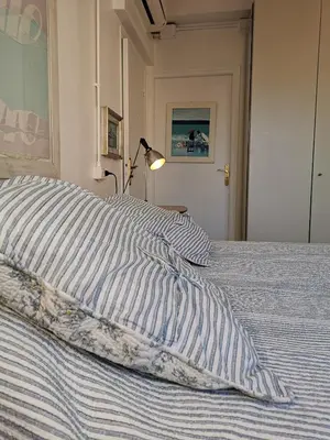 a bed with a blue and white striped pillow and a lamp at Karol in Cannes