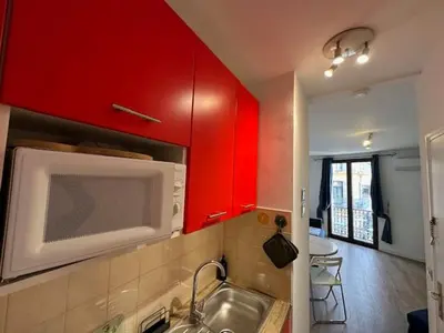 a kitchen with red cabinets and a sink and a microwave at Mark in Cannes