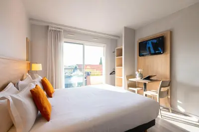 a bedroom with a large white bed with a window at Zenitude Hôtel-Résidences Le Cannet in Le Cannet