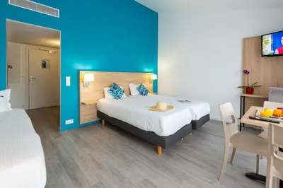 a hotel room with a bed and a desk with a table at Zenitude Hôtel-Résidences Le Cannet in Le Cannet