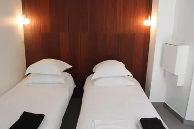two beds in a small room with wood paneling at Villa Le Ruisseau in Cannes