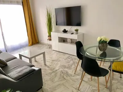 a living room with a glass table and a tv at Residences Fleuries - behind Cannes Croisette Bvd in Cannes