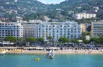 a large white building on a beach with a boat in the water at Residences Fleuries - behind Cannes Croisette Bvd in Cannes
