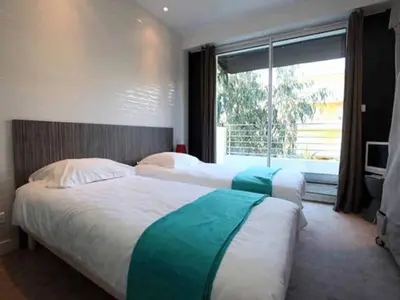 two beds in a hotel room with a window at Villa Roi Albert 2 in Cannes