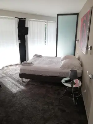 a bedroom with a bed and a chair and a window at Villa Roi Albert 2 in Cannes