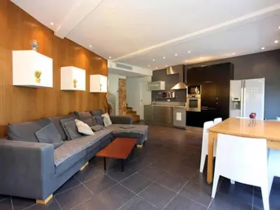 a living room with a couch and a table and a kitchen at Villa Roi Albert 2 in Cannes