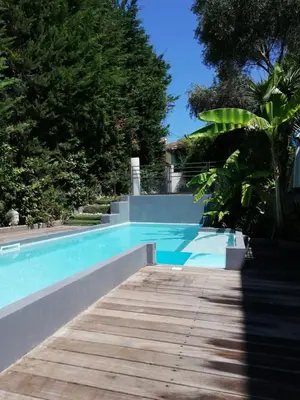 a blue swimming pool with a wooden walkway at Villa Roi Albert 2 in Cannes