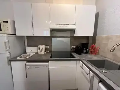 a white kitchen with white cabinets and appliances at Appartement moderne à Cannes, 45 m², proche des plages in Cannes