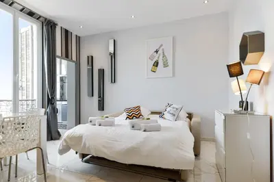 a white bedroom with a bed and a tv at IMOOGROOM - Modern - City Center - AC - 9 min from the Palais in Cannes