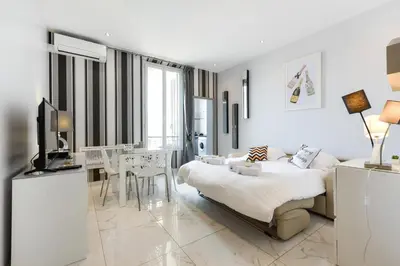 a white bedroom with a bed and a dining room at IMOOGROOM - Modern - City Center - AC - 9 min from the Palais in Cannes