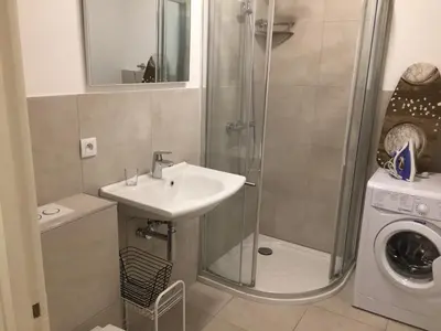a bathroom with a shower and a sink and a washing machine at Grand Studio Carré d'Or - Les Méridiens in Cannes