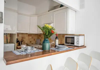 a kitchen with white cabinets and a table with a vase of flowers at Cannes Apartment 3 mins from the beach in Cannes